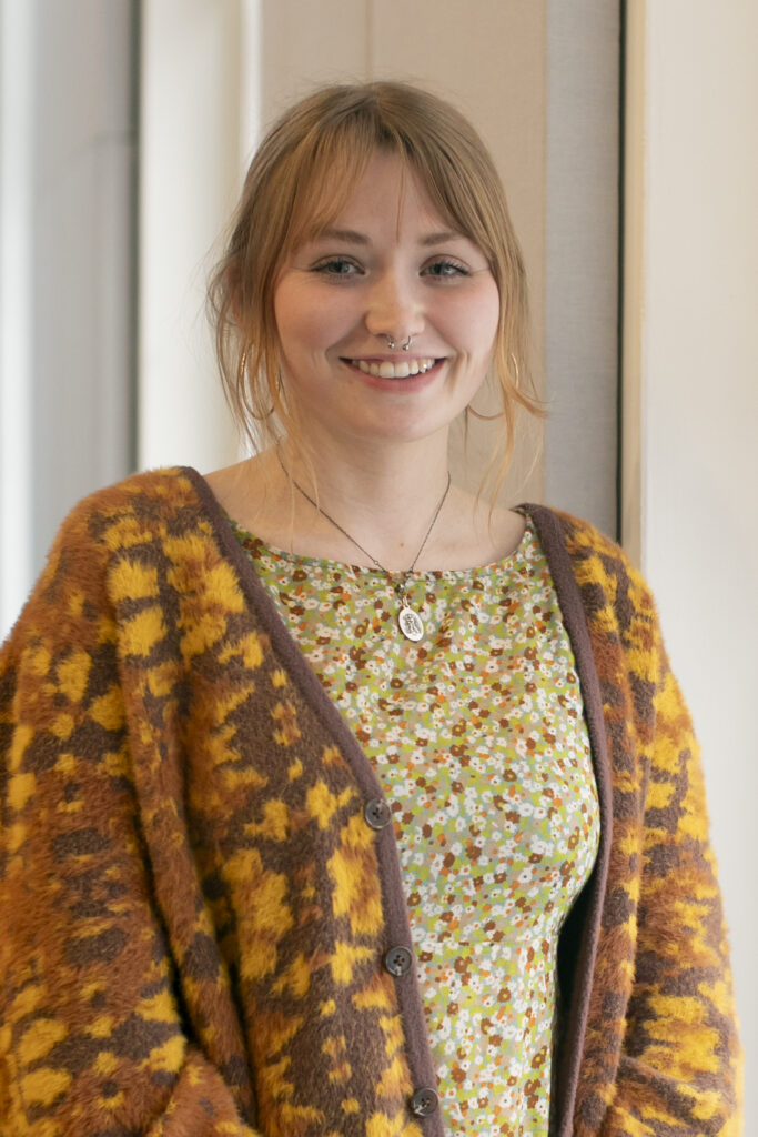 Chloe Adler stands near a window