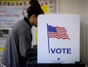 a female voting at a voting booth that says "vote" on it.