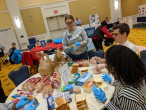 Three students prepare sandwiches for MLK Day of Service. 