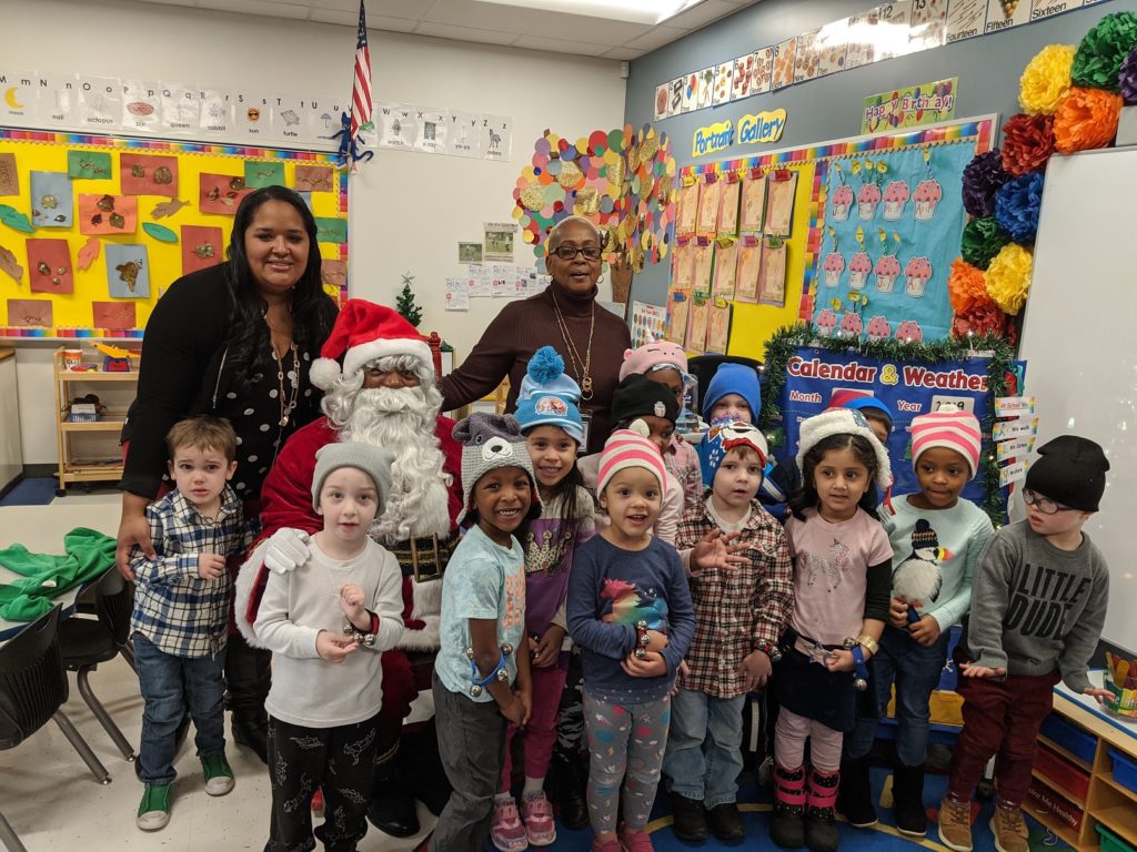 Two women pose with a class of pre-school students.