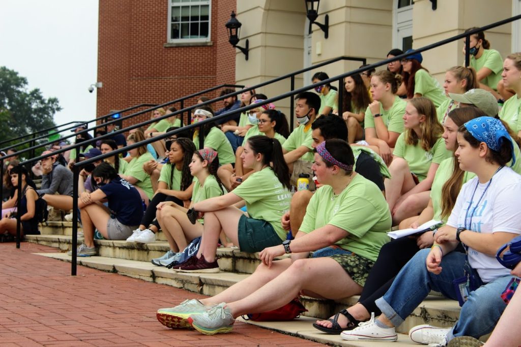 Students sit on the steps of the CRUC in their green COAR t-shirts. 