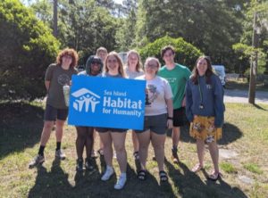 Group of eight students holding a Habitat for Humanity sign.