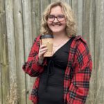This is Emma holding a coffee with short blond hair and a flannel