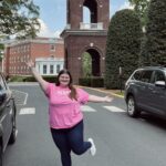 Erin, wearing a pink shirt and standing in front of UMW Bell Tower.