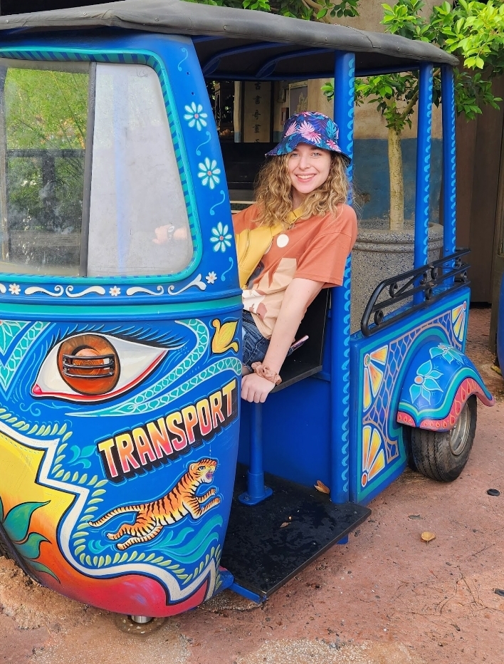 Molly, with blonde curly hair, wearing a blue hat, in a blue truck.