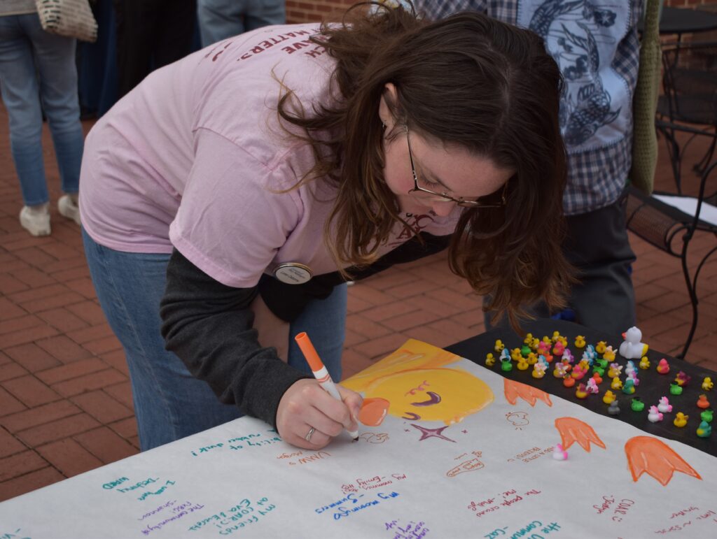 student signing the Pay it Forward Day Banner