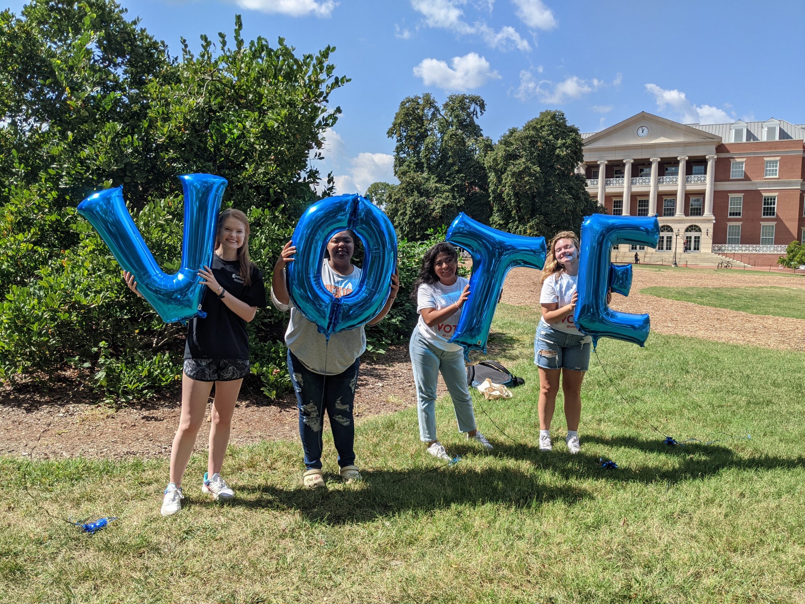 Four students holding balloons that spell out "VOTE"
