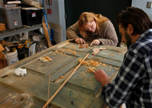 A UMW intern works with the Manager of Restoration on an original front door in the restoration lab at Mount Vernon. 