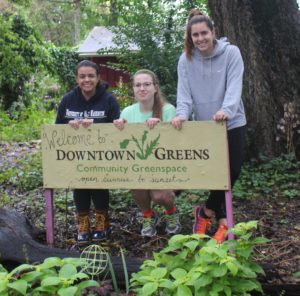 students standing by Downtown Greens sign